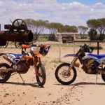 Two dirt bikes in front of a Bulloo Downs sign