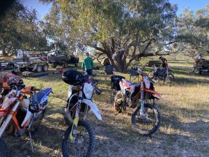 A group of motorbike riders setting up camp under a tree