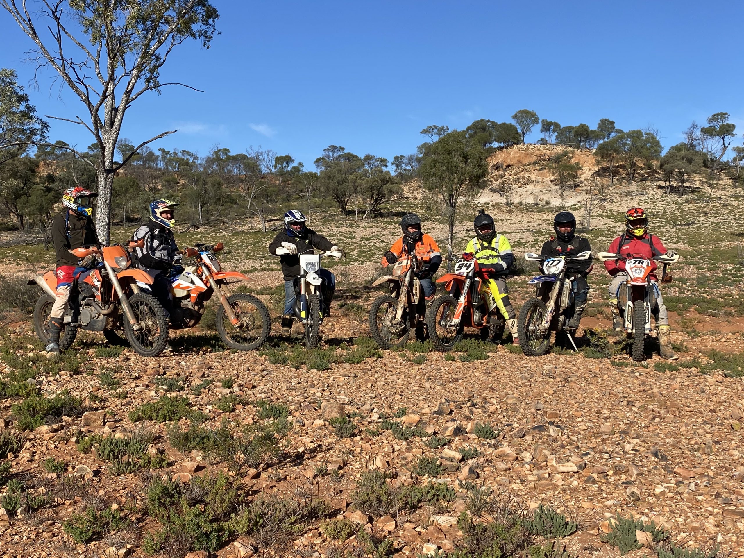 A group of dirt bike riders sitting on their bikes