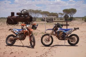 Two motorbikes in front of a Bulloo Downs sign