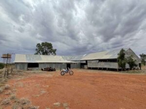 A motorbike in the desert in front of a shed
