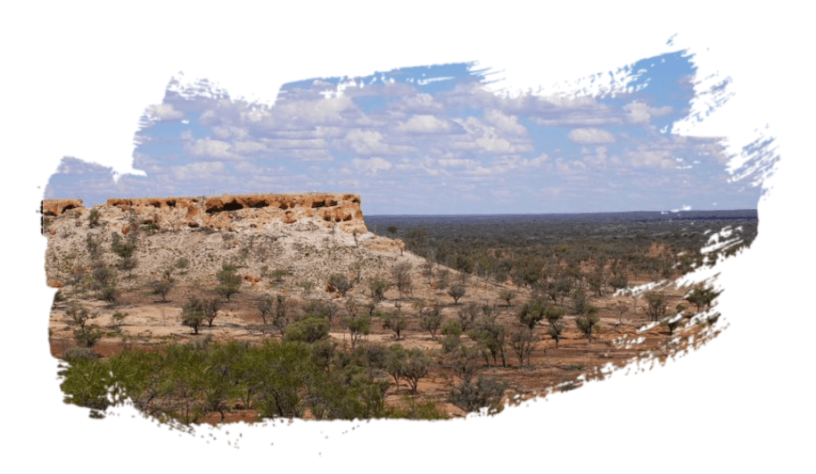 An image of an outback scene with trees and a rocky outcrop