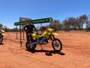Man Posed Next To Bike And Road Sign