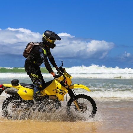 Dirt bike rider riding through the ocean on Rainbow Beach