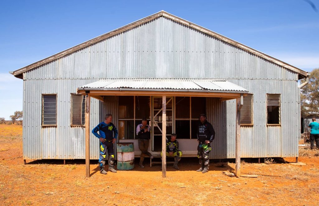 A group of people sitting in front of an old shed